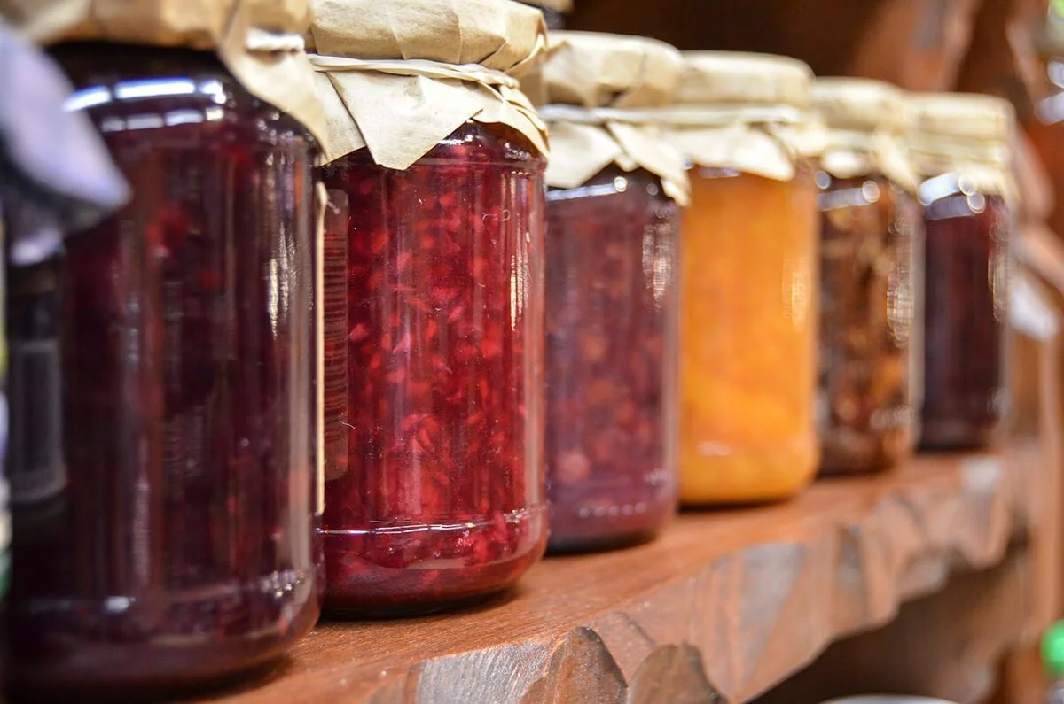 Glass jars of jams on wooden shelf